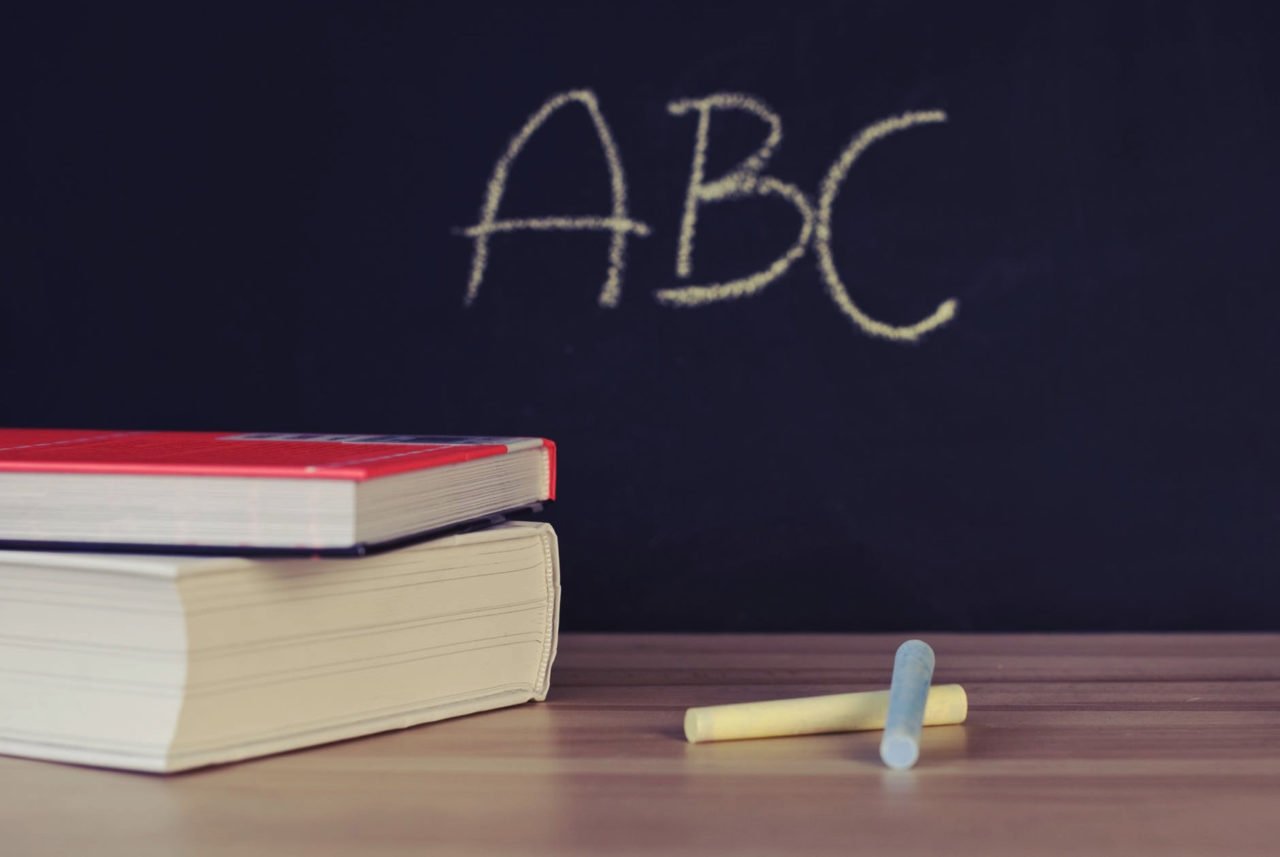 abc on blackboard next to books and chalk