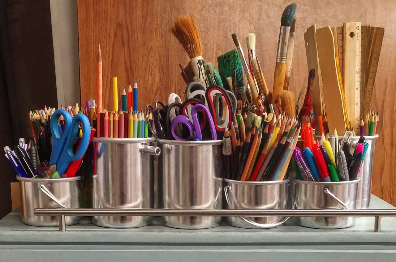 cups full of pens, pencils, paint brushes, and rulers