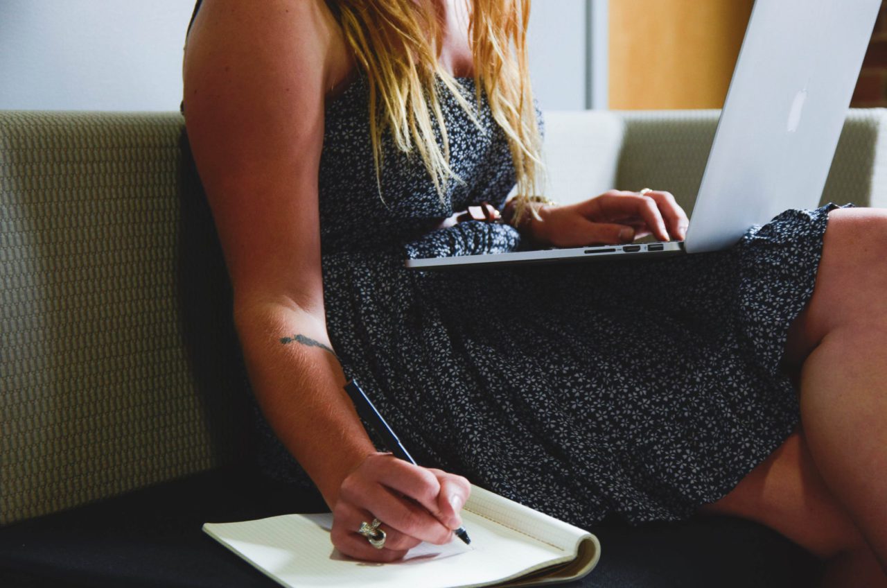 Girl using computer and writing on notepad